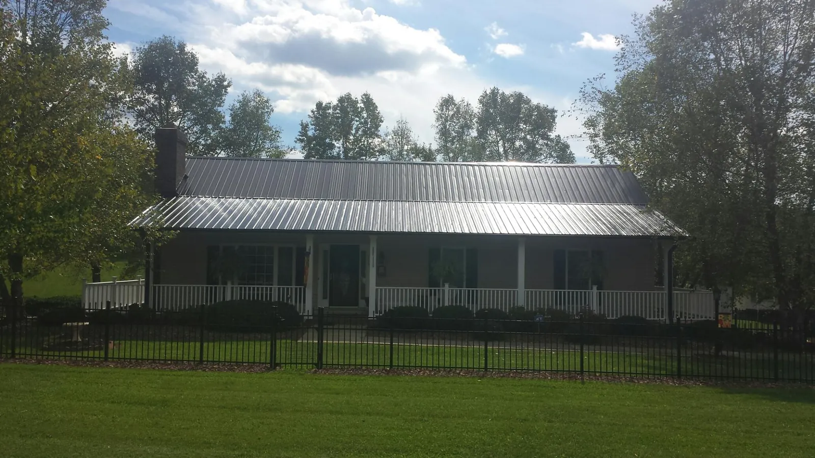 Gray metal roof on a brick ranch with a full width front porch in Corunna